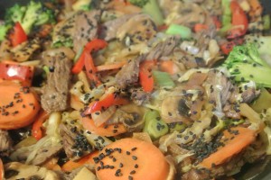 Beef stirfry with tamari, ginger, garlic, and black sesame seeds served over brown rice vermicelli noodles