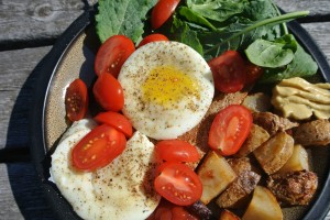 Breakfast for supper: 2 poached eggs, roasted potatoes, and baby grape tomatoes and baby kale leaves served over a slice of gluten-free toast